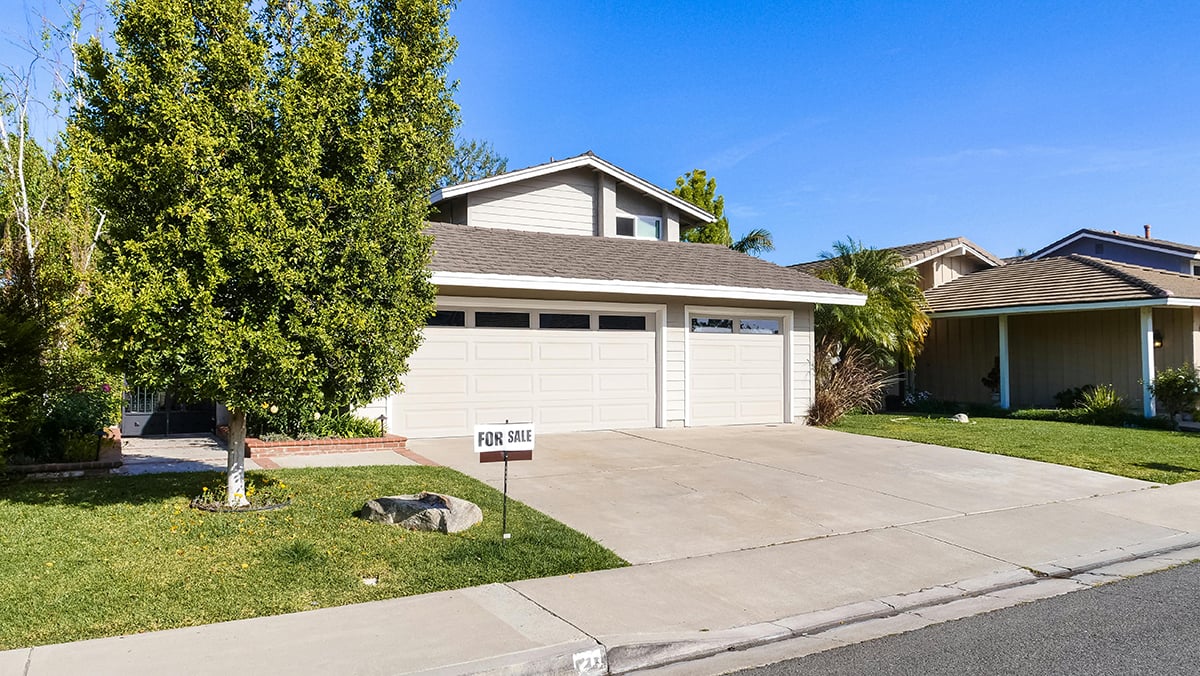 A single-family home on a suburban street with a for sale sign in front
