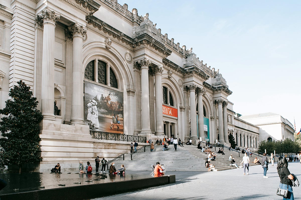 The exterior of the Metropolitan Museum of Art and people hanging out on a sunny day