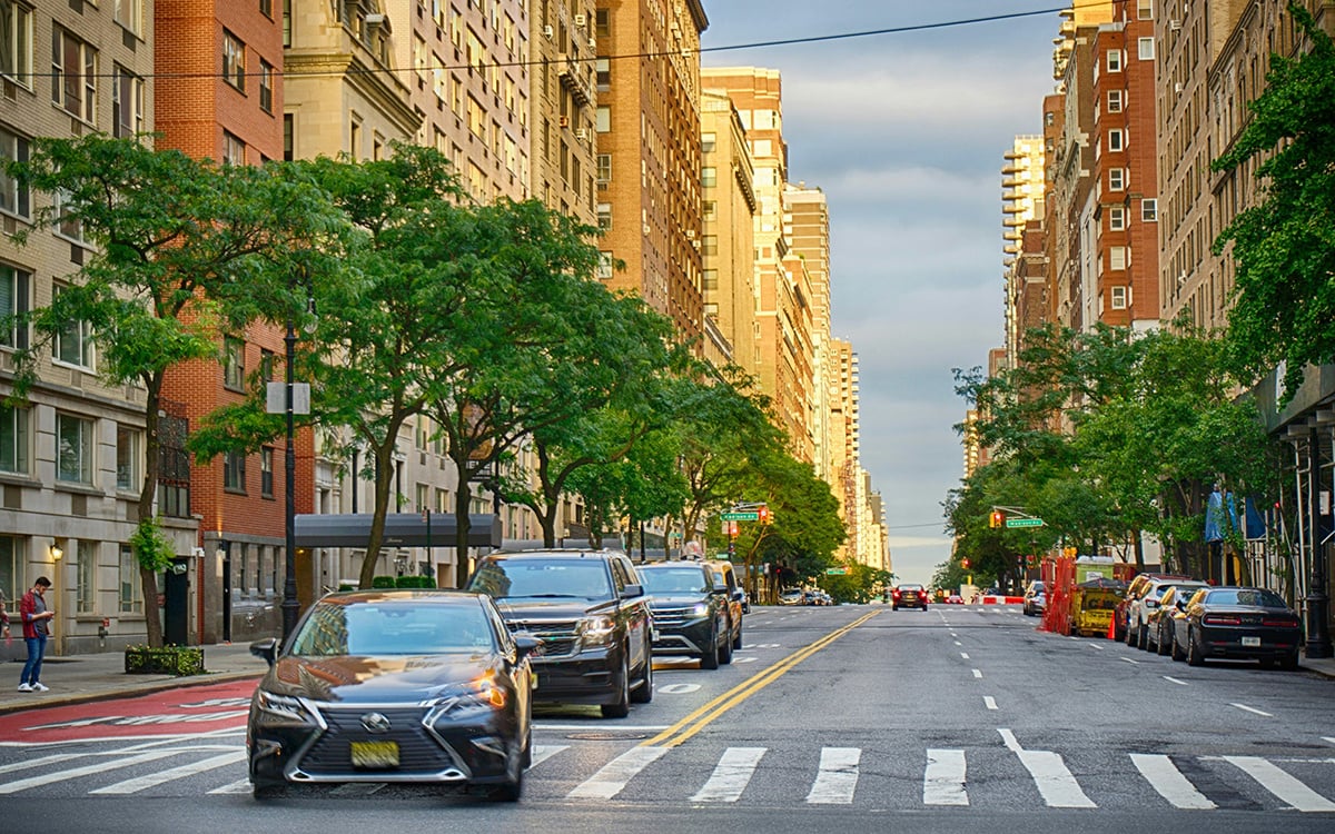 Cars driving down 5th Avenue in the Upper East Side at dusk 