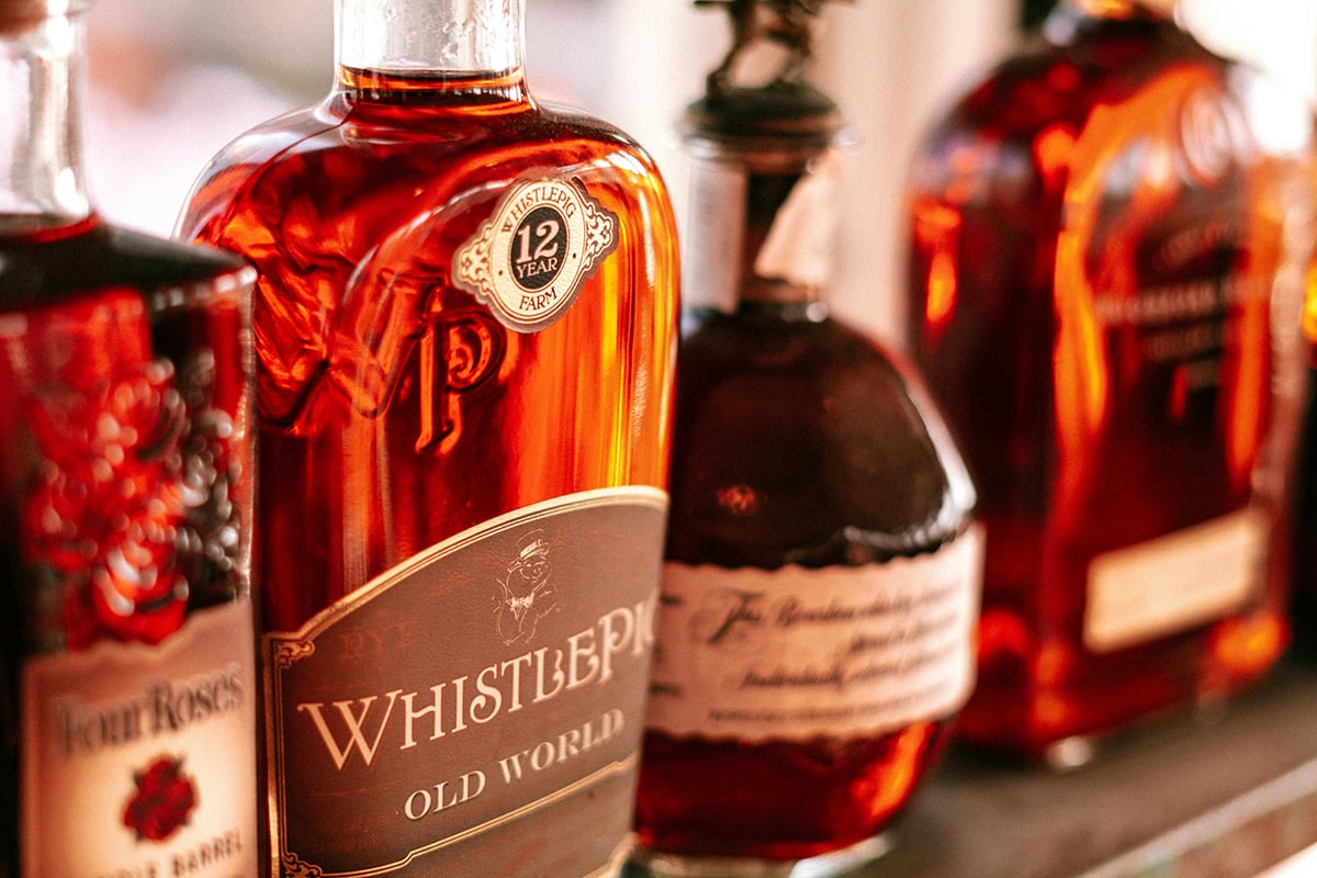 Bottles of whiskey lined up along a wall.