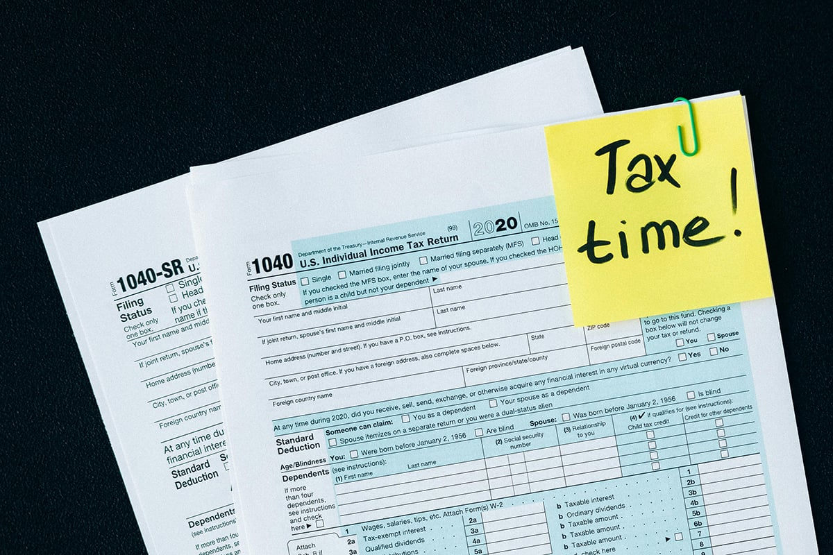 Individual income tax forms with a yellow sticky note that says “tax time”