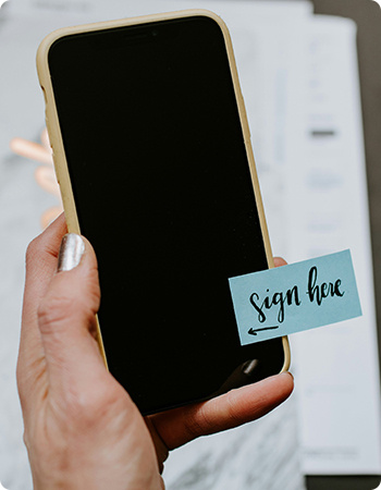 hand holding iPhone with sticker "sign here" hand holding iPhone with sticker "sign here"